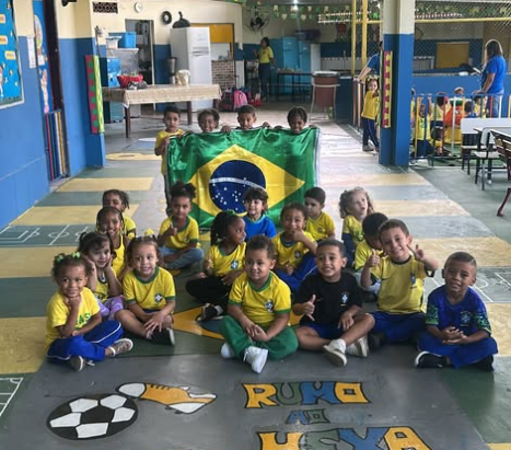 Turma reunida com a bandeira do Brasil no pátio decorado